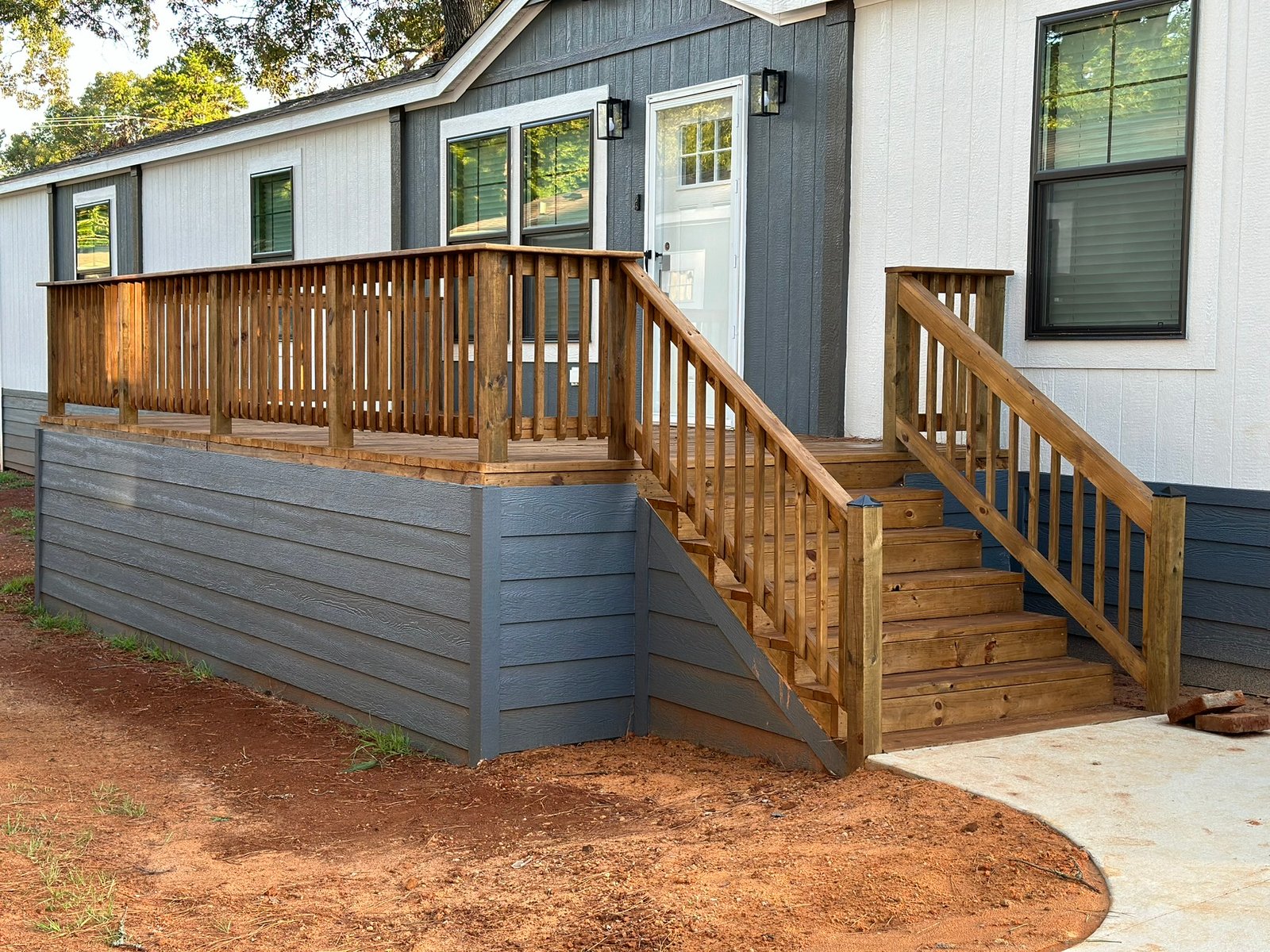 A finished deck with wood railing and stairs built by Bluebonnet Home Resolutions on a North Texas mobile home