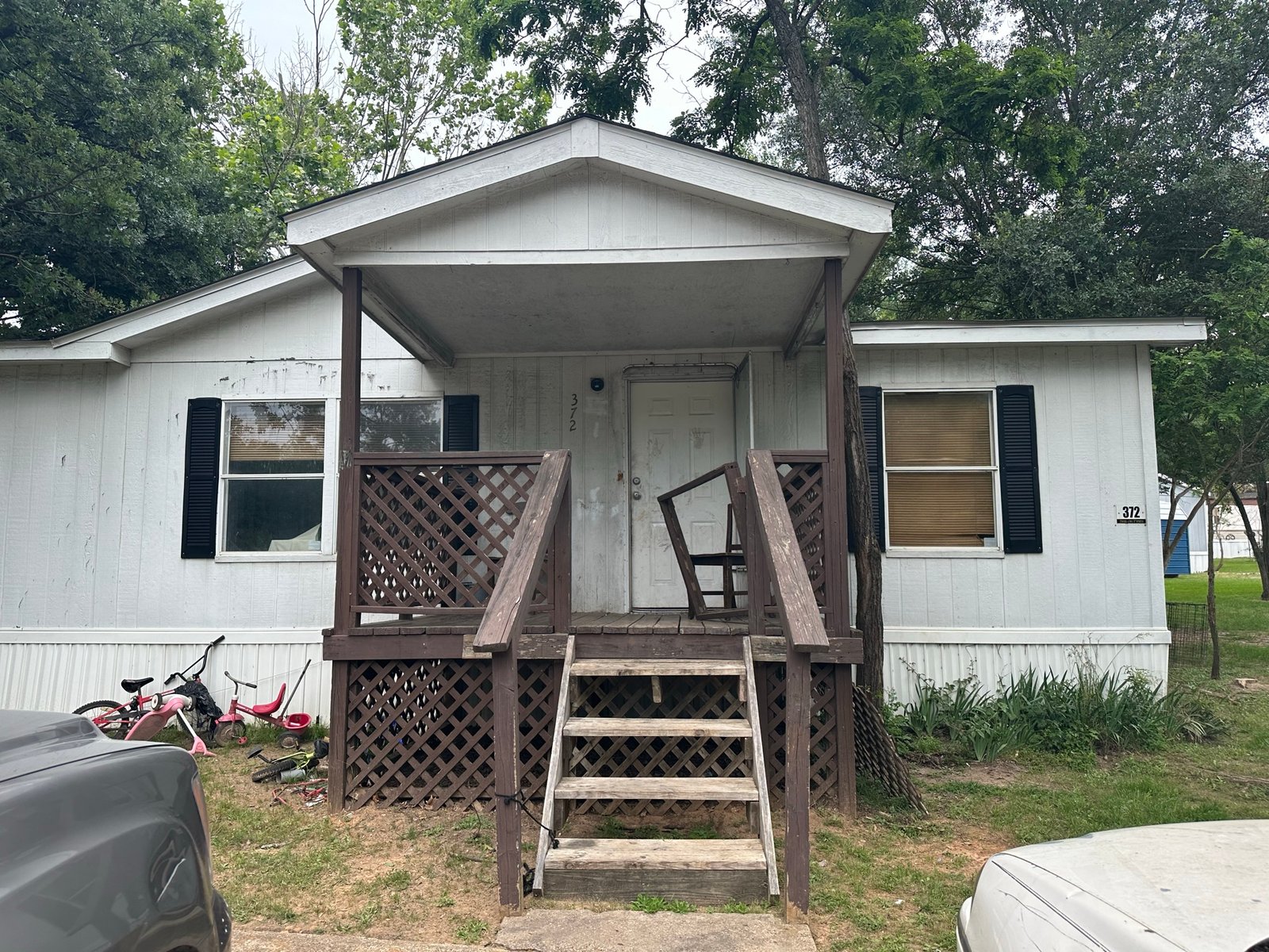 Mobile home before a full exterior remodel, worn siding and porch railing