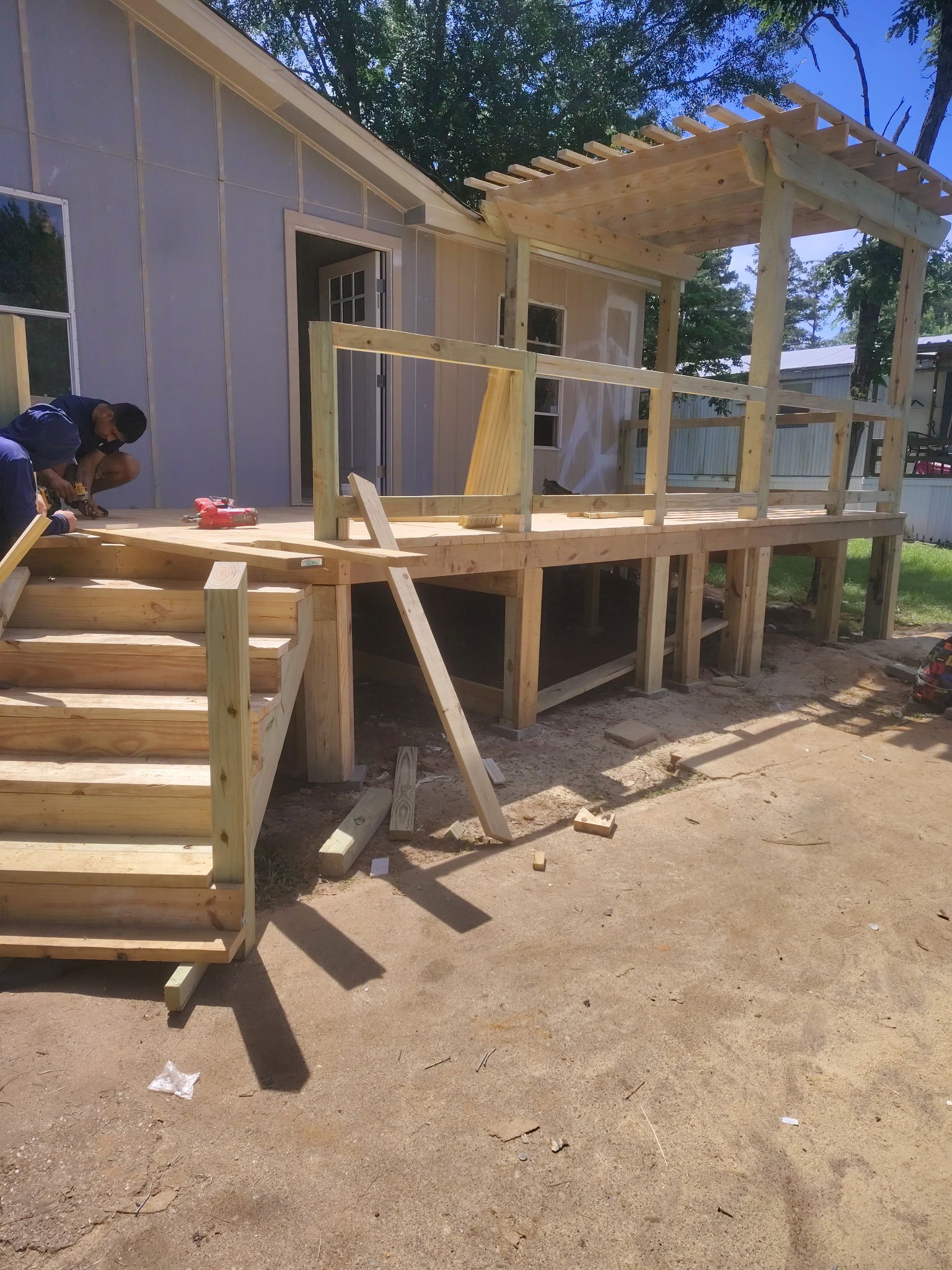 Deck and pergola framing continuing during a full exterior remodel