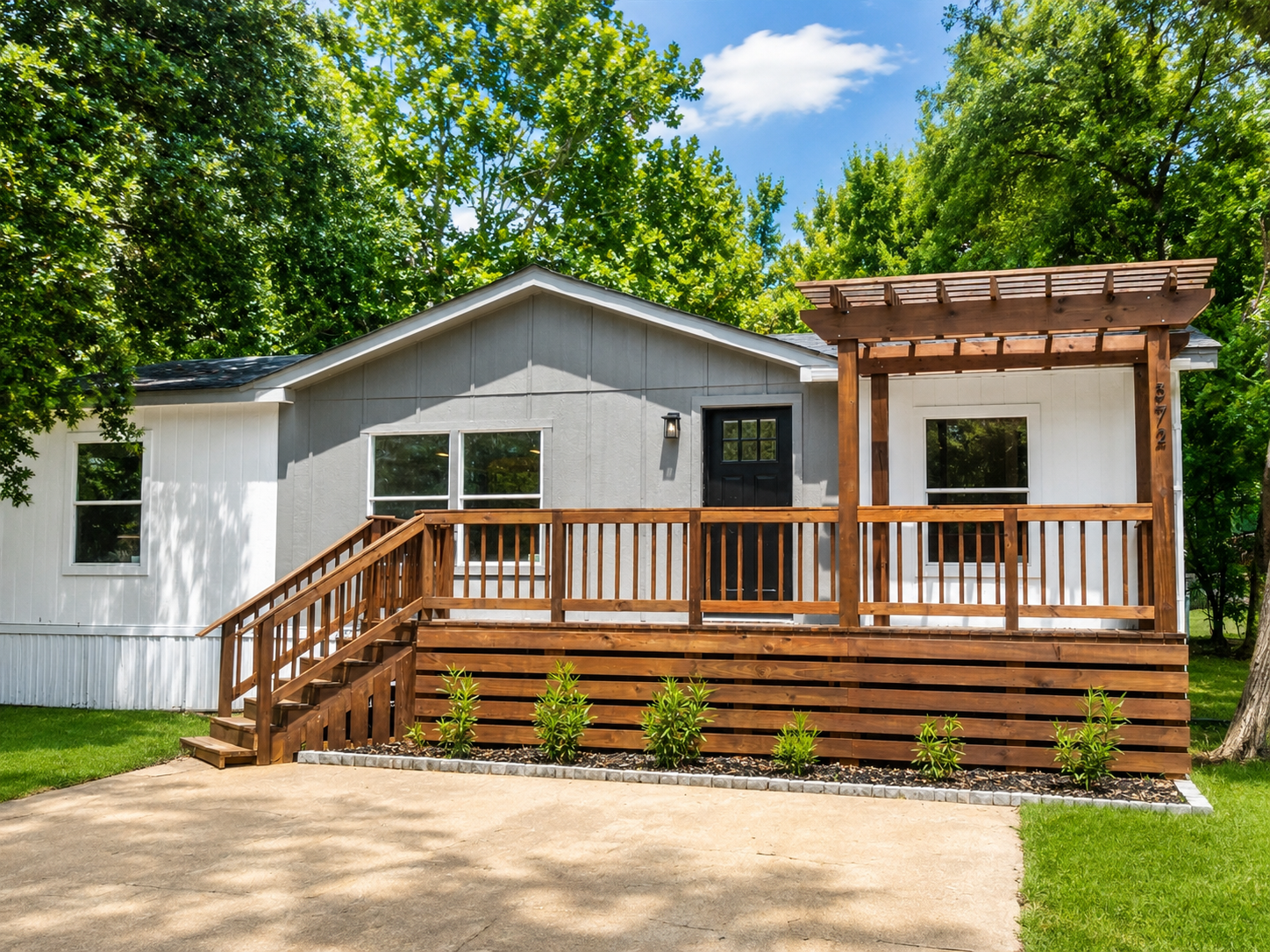 Finished full exterior remodel with light gray siding, wood pergola deck, and new landscaping
