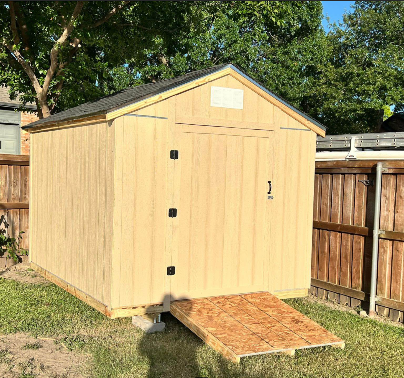 Newly built wood storage shed with a gable roof and ramp in a North Texas backyard